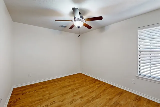 an empty room with a window and a fan