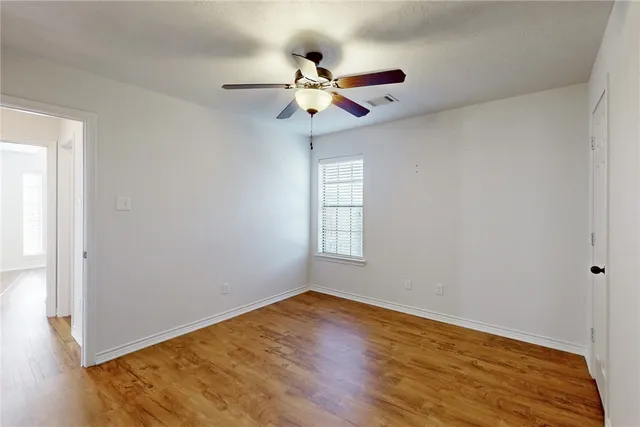 a view of a room with wooden floor fan and windows