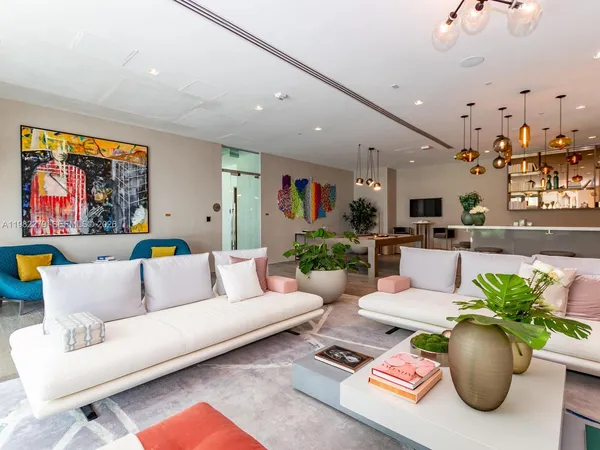 a living room with furniture potted plant and kitchen view