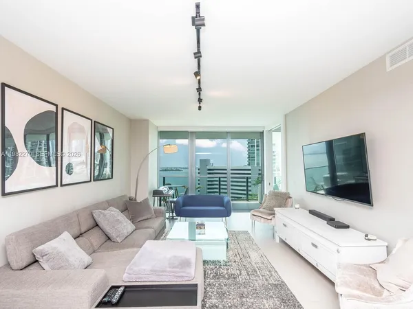 a living room with furniture a flat screen tv and a large window