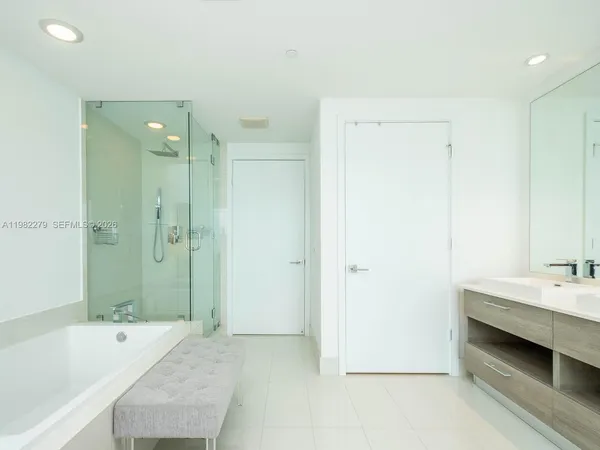 a bathroom with a tub sink shower and two mirror
