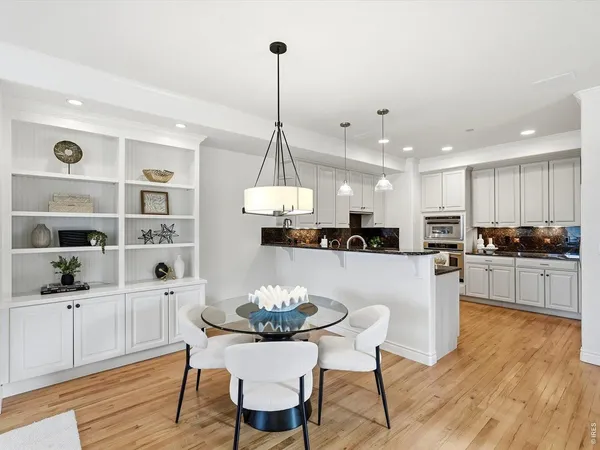 a kitchen with stainless steel appliances kitchen island granite countertop a sink a stove a dining table and chairs