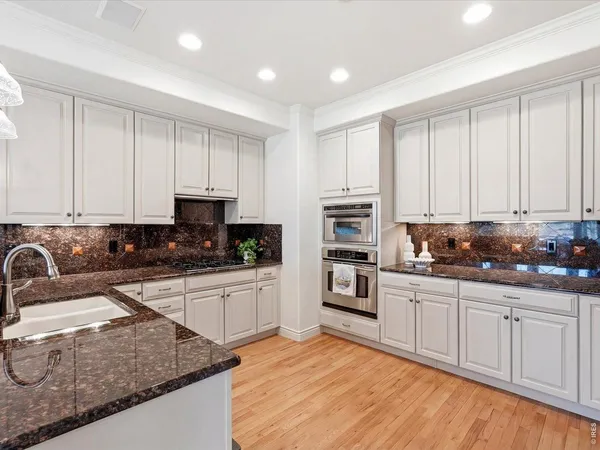 a kitchen with granite countertop white cabinets and stainless steel appliances