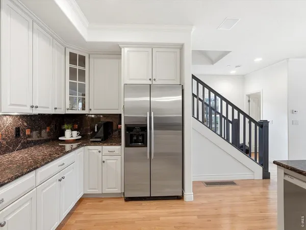 a kitchen with granite countertop a refrigerator a sink and wooden cabinets