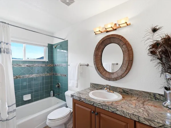 a bathroom with a granite countertop sink a toilet and a mirror
