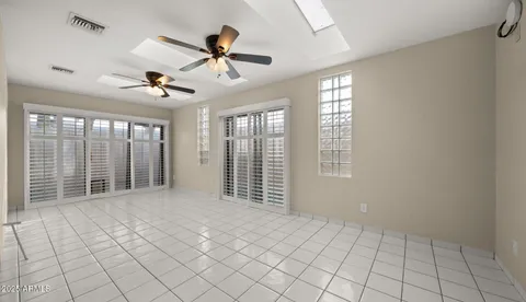 a view of a big room with windows and chandelier fan