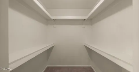 a view of an empty room with window and chandelier fan