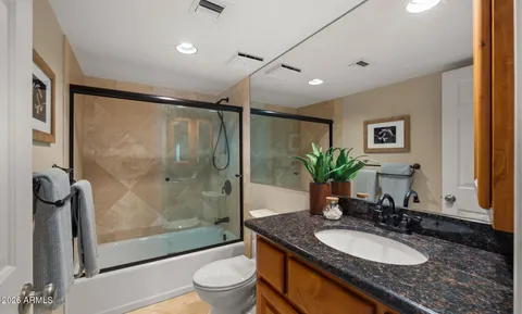 a bathroom with a granite countertop sink a toilet a mirror and shower
