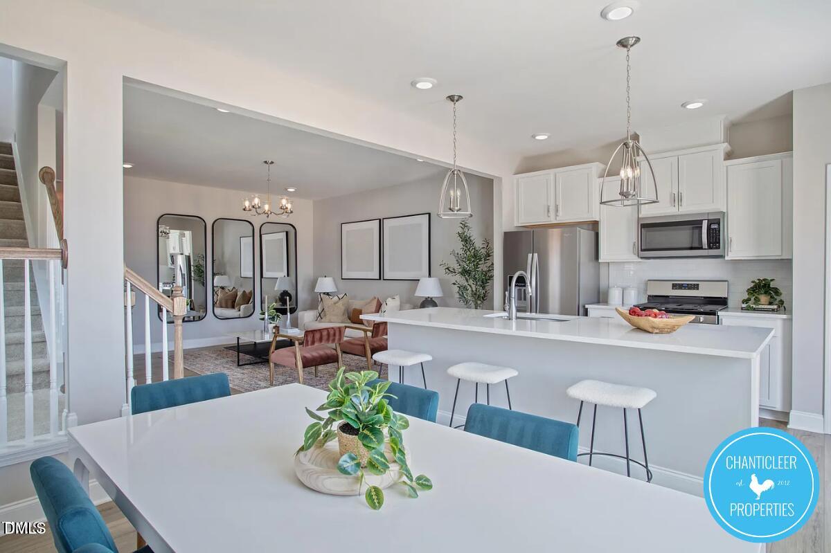 24 Hyacinth Lane, Unit 99 Angier, NC 27501 - Photo 3 of 9 a kitchen with stainless steel appliances a dining table chairs and white cabinets