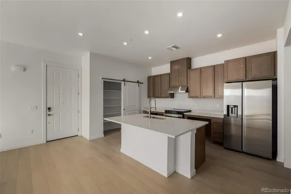 a kitchen with stainless steel appliances granite countertop a refrigerator a stove and a sink