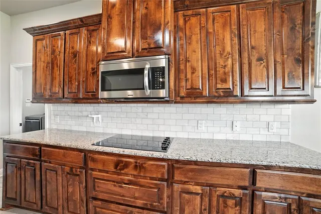 a kitchen with stainless steel appliances granite countertop a sink a microwave cabinets and a granite counter top