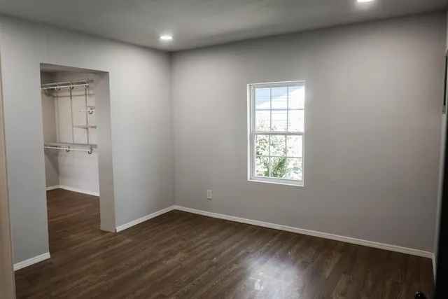 an empty room with wooden floor and windows