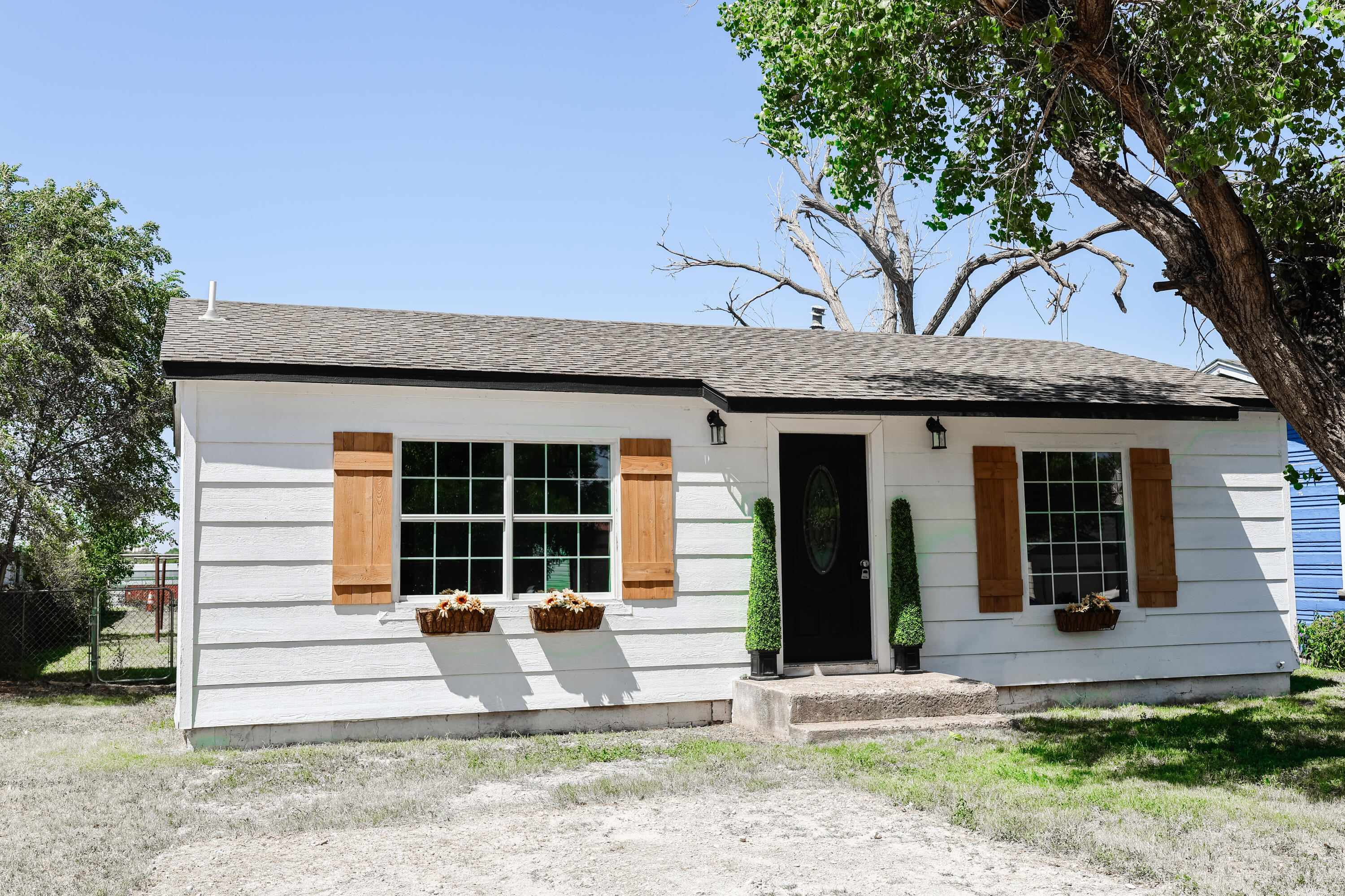 112 Southwest 8th Plainview, TX 79072 - Photo 3 of 24 a front view of a house with a large tree and table and chairs in patio