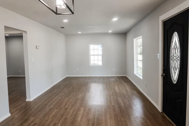 an empty room with wooden floor and windows