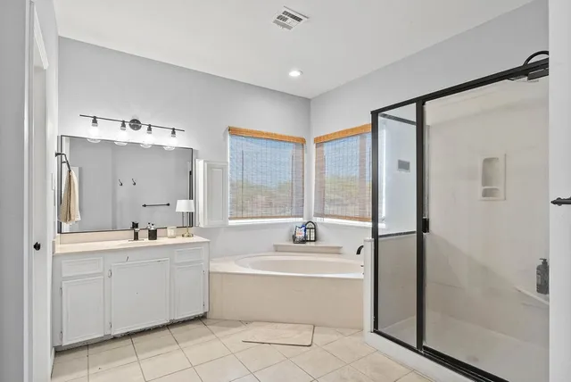a bathroom with a tub sink shower and mirror