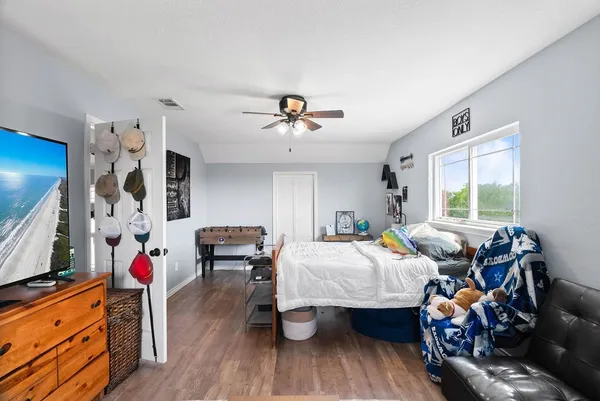 a bedroom with bed and a flat tv screen on dresser