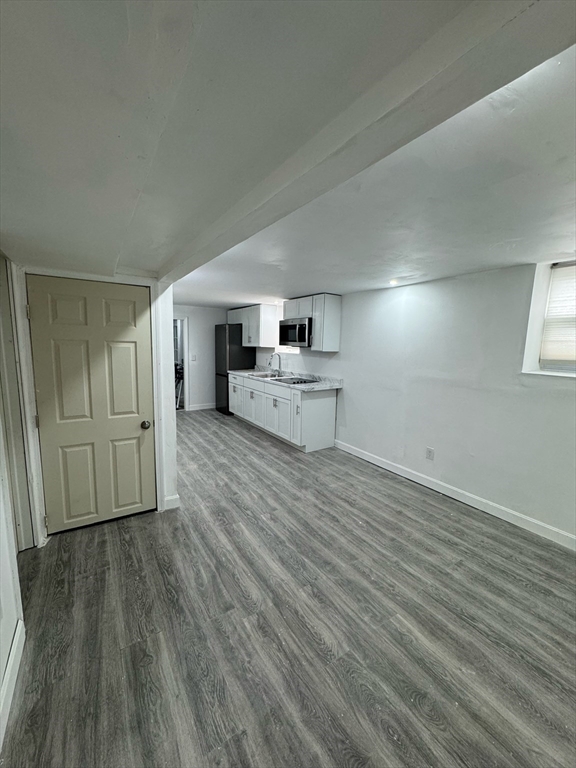 244 Wilbur Street, Unit 3 Fall River, MA 02724 - Photo 6 of 21 an empty room with wooden floor cabinet and windows