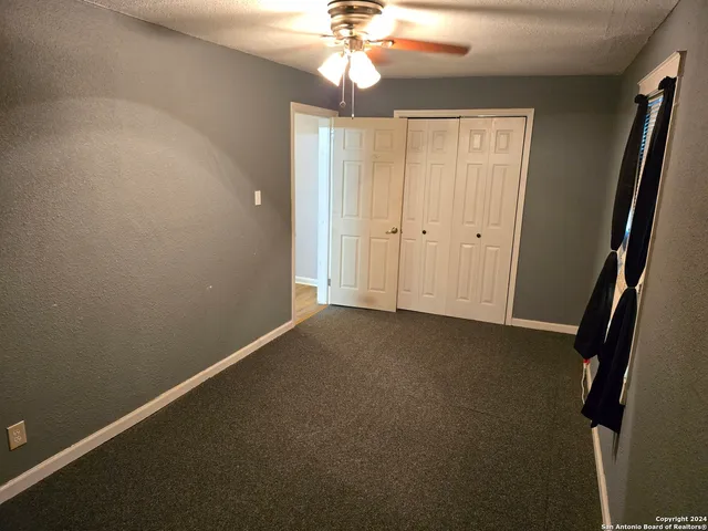 an empty room with windows and fan