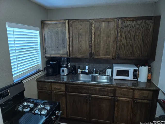 a kitchen with a sink a stove and cabinets