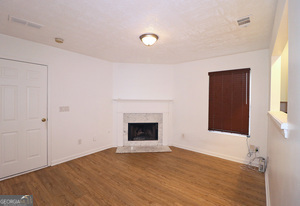 5851 Giles Road Lithonia, GA 30058 - Photo 6 of 15 a view of an empty room with wooden floor and a window