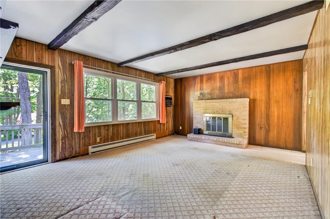 18 White Oak Road Nesquehoning, PA 18240 - Photo 10 of 52 A rustic living area with exposed wood beams and paneling, featuring a brick fireplace.