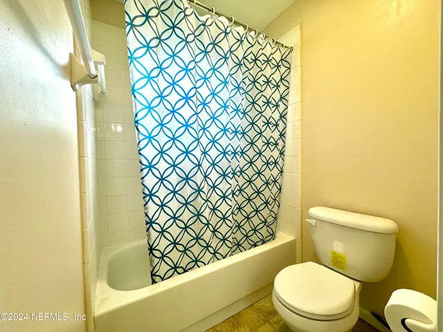 a white toilet sitting next to a shower curtain