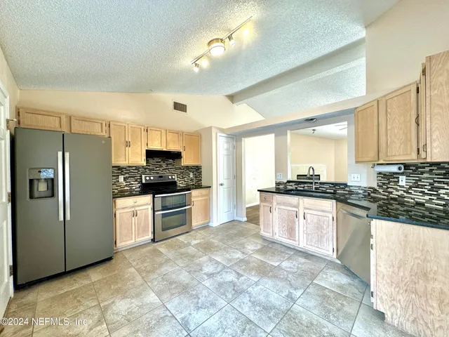 a kitchen with stainless steel appliances granite countertop a stove a sink dishwasher a refrigerator and a oven