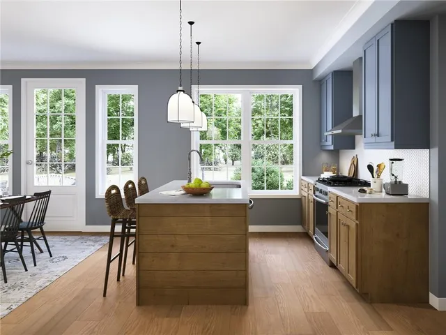 a kitchen with kitchen island granite countertop a stove a sink a dining table and chairs with wooden floor