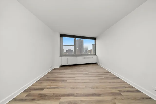 a view of an empty room with wooden floor and a window