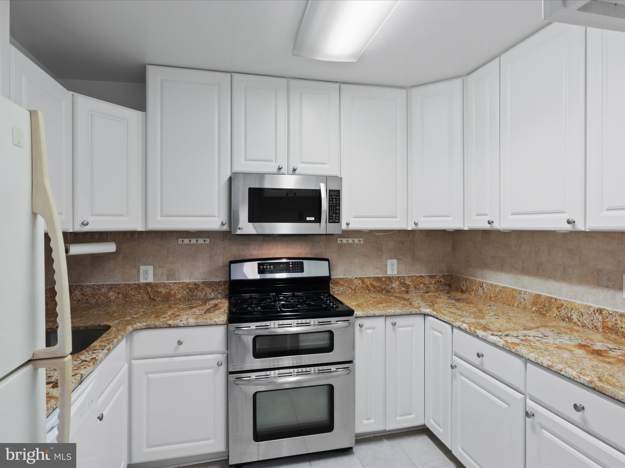 5101 River Road, Unit 1807 Bethesda, MD 20816 - Photo 14 of 32 a kitchen with white cabinets and stainless steel appliances