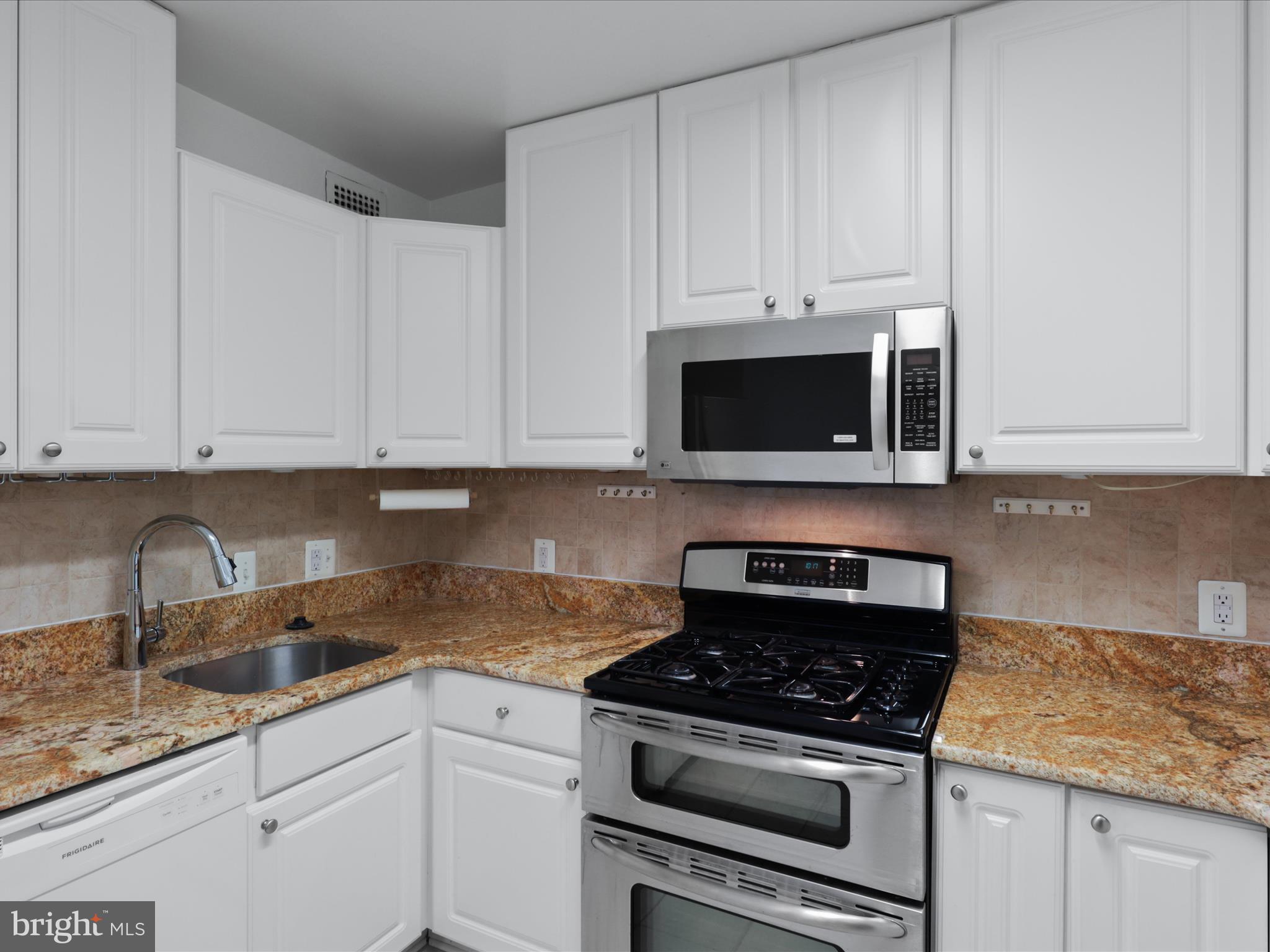 5101 River Road, Unit 1807 Bethesda, MD 20816 - Photo 15 of 32 a kitchen with granite countertop white cabinets and stainless steel appliances