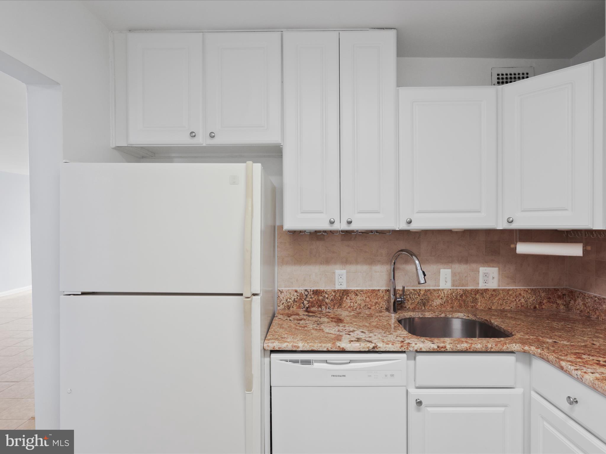 5101 River Road, Unit 1807 Bethesda, MD 20816 - Photo 16 of 32 a kitchen with granite countertop white cabinets and a refrigerator