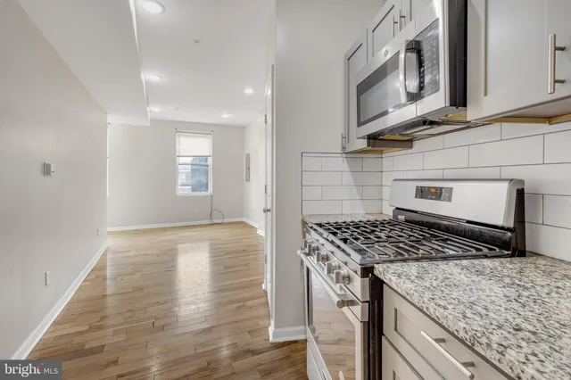 a kitchen with stainless steel appliances granite countertop a stove a sink and a microwave