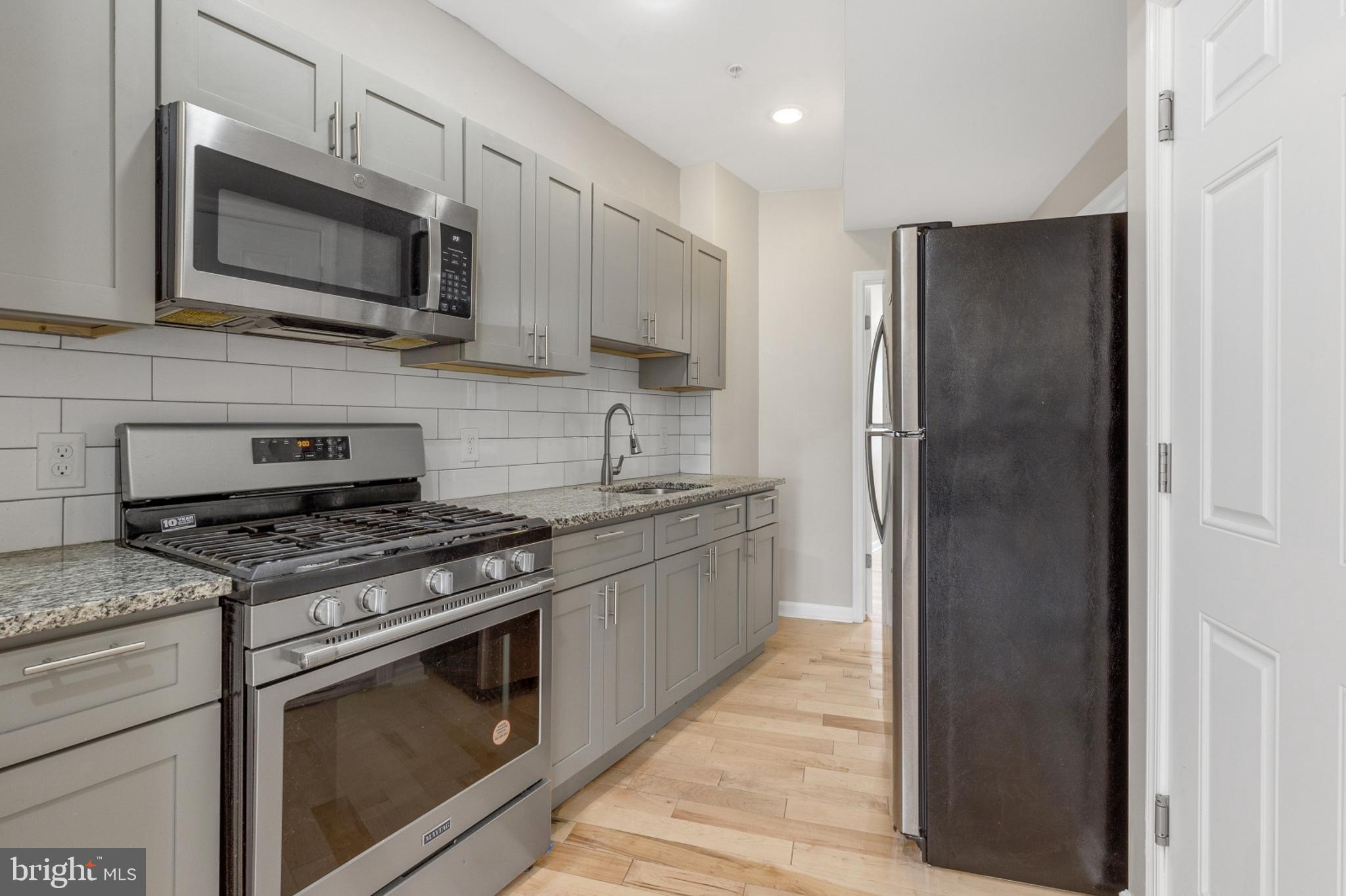 2604 Frankford Avenue, Unit 3 Philadelphia, PA 19125 - Photo 4 of 13 a kitchen with stainless steel appliances granite countertop a stove a refrigerator and a microwave