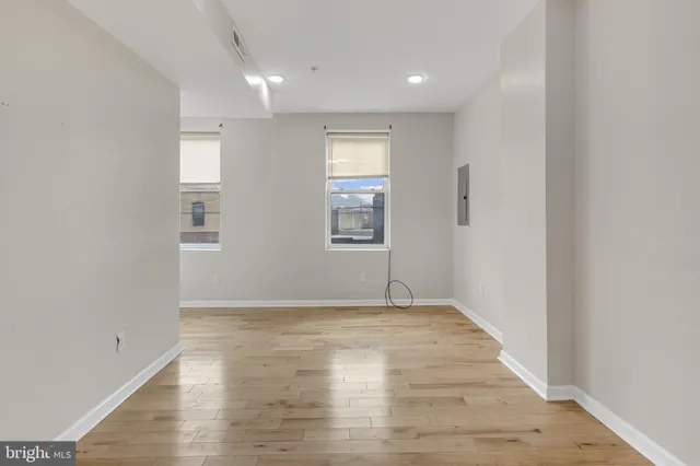 a view of empty room with wooden floor and fan