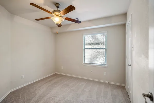an empty room with closet and a chandelier fan