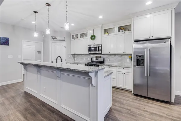 a kitchen with stainless steel appliances granite countertop a refrigerator a sink a stove a dining table and chairs