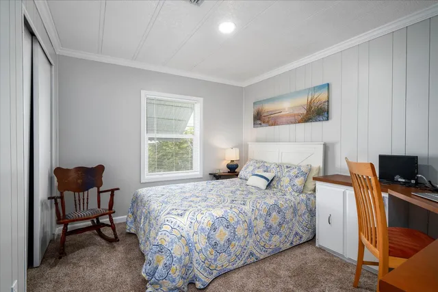 a bedroom with a bed table chair and a window