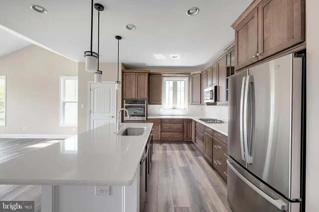 a large kitchen with a refrigerator a sink dishwasher a stove and white cabinets with wooden floor