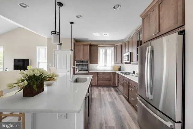 a kitchen with stainless steel appliances a refrigerator a sink a stove and white cabinets