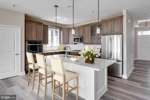 a kitchen with stainless steel appliances granite countertop a refrigerator a oven a sink a dining table and chairs with wooden floor