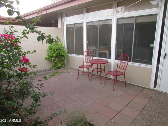 a patio with table and chairs and potted plants