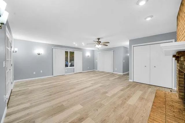 a view of an empty room with wooden floor and a kitchen