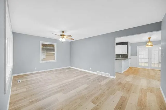 a view of an empty room with window and wooden floor