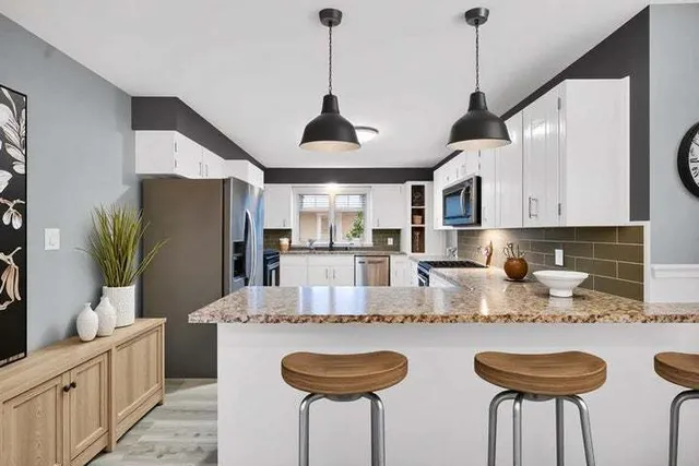 a kitchen with stainless steel appliances granite countertop a sink a refrigerator and a white cabinets