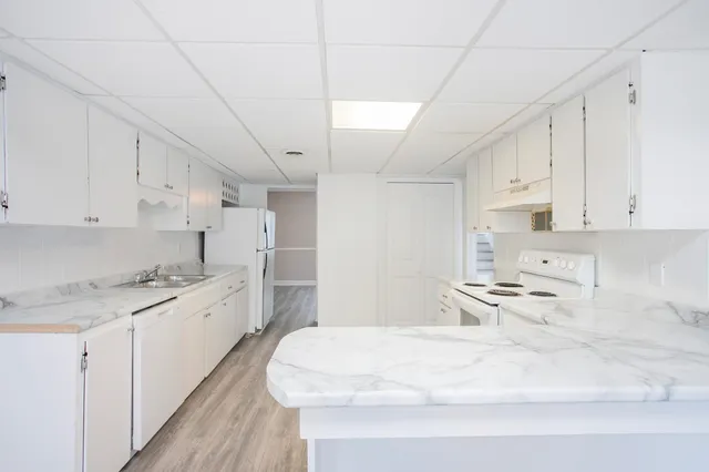 a kitchen with kitchen island a sink a stove a refrigerator and white cabinets