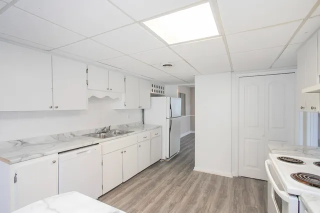 a kitchen with stainless steel appliances white cabinets and wooden floors