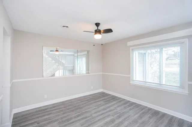 a view of an empty room with wooden floor and a window