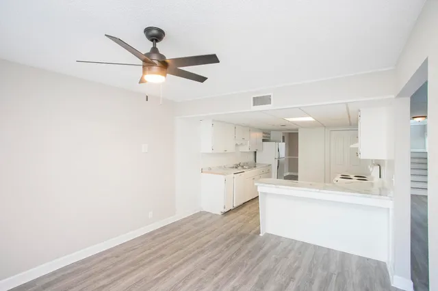 a view of a kitchen with wooden floor and a ceiling fan