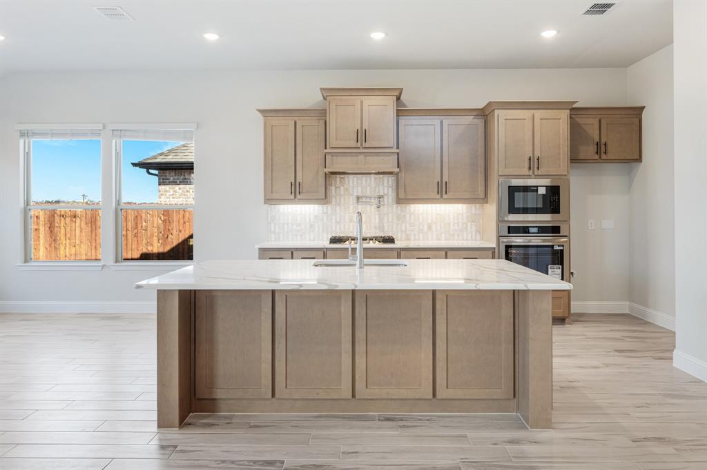 2411 Cornwall Lane Forney, TX 75126 - Photo 13 of 40 a kitchen with kitchen island granite countertop a stove and a sink